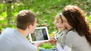 stock-footage-happy-family-using-tablet-pc-outdoors-in-autumn-park.webp